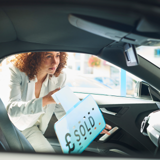 Woman adding a sold sign to a car