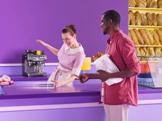 Image of two people at a counter with one person ready to pay with a card machine