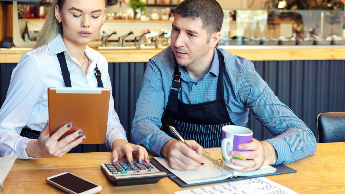 Two people at a table looking with a calculator and and paperwork