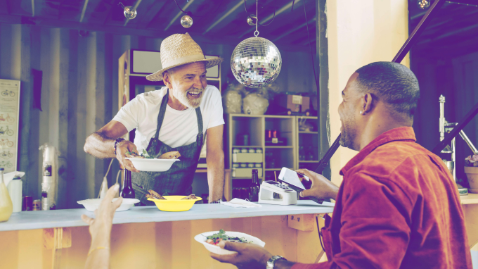 A person selling food to someone using their phone to pay by contactless